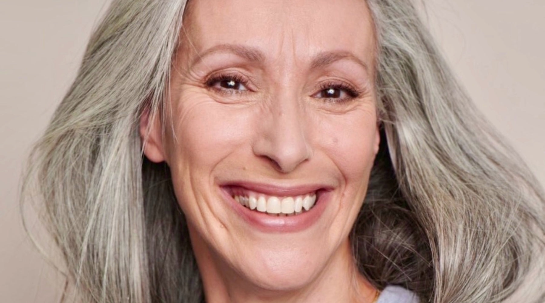 une belle femme mature avec un maquillage naturel, utilisant un anti-cernes qui rajeunit son regard